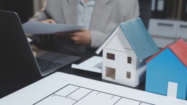 Emlakçı ev modeli üzerinde sözleşme gösteriyor, yakın plan.