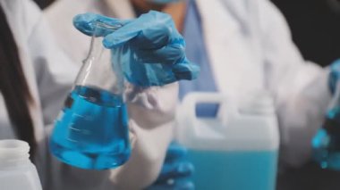 Yakın plan. Mavi eldivenli bir laboratuvar asistanı tüpte sıvı tutuyor. Tıp konsepti. Bilim ve araştırma