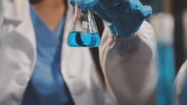 Koruyucu giysili bilim adamı laboratuvarda aşıyla tüp tutuyor.