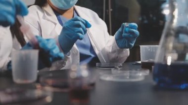 Üniformalı ve gözlüklü genç kadın bir kimyasal deney üzerinde çalışıyor..