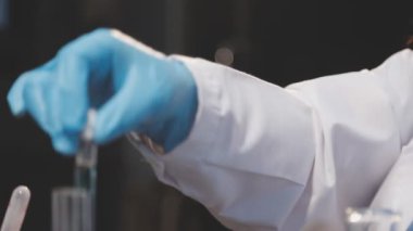 Laboratuvarda mikroskopla koruyucu eldivenler giyen bilim adamı.