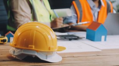 Mühendis ya da mimar ofis masasında ev planıyla birlikte taslak üzerinde çalışıyor..