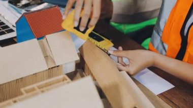 Ahşap tahta ve cetvelle ahşap masada çalışan genç bir adam. Marangoz ve marangoz ağaçta çalışıyor..