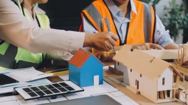 Ofiste çalışan mühendis ya da mimar ev modeli ve planıyla, inşaat alanı ve planıyla. Emlak kavramı