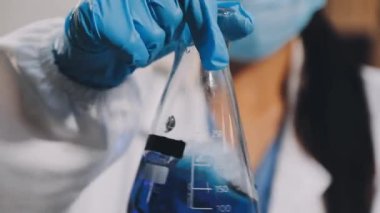 Laboratuvar çalışanı elinde bir bardak su tutuyor.