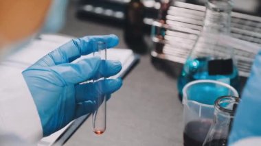 Laboratuvarda bir bardakla sıvı tutan bir bilim adamı.