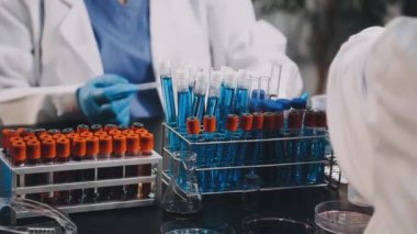 Kapat. Koruyucu eldivenler giymiş bilim adamı laboratuarda kanla test tüpü tutuyor.