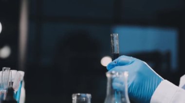 Laboratuvarda elinde matarayla duran erkek bilim adamının yakın çekimi.