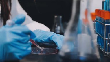 Laboratuvarda bir bilim adamı cam bardakla laboratuvarda sıvı tutuyor. Sıvı tüple kadın elinin fotoğrafını kapat..