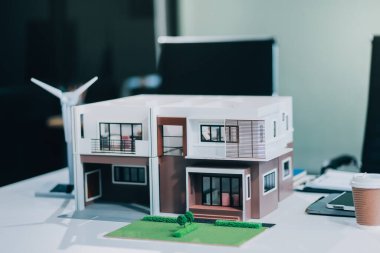 Rüzgar türbini modeli ve ev modeli için mühendisler buluşuyor. Yenilenebilir enerji ve konut geliştirme kavramı. Modern ofiste mimarlardan ve mühendislerden oluşan bir ekip tasarım yapısını tartışıyor..