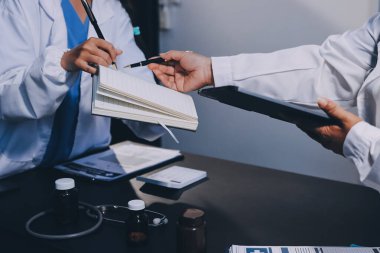 Hastane tıbbı çok etik insanlar grup toplantısı ekibi, aşı eğitimi için hemşire öğrencilerle klinik odasında konuşma. Tablet ve pano tutuluyor.