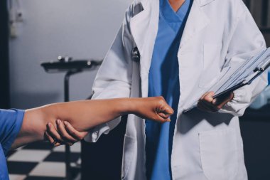 Doktor ya da fizyoterapist, sporcu erkek hastaların yaralı kollarını tedavi ediyor, esneme ve egzersiz yapıyor, klinikte rehabilitasyon tedavisi uyguluyor..