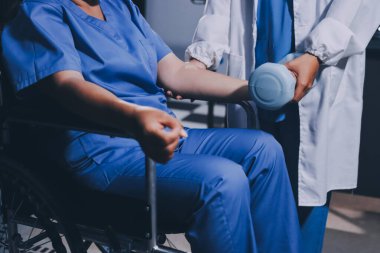 Evde dambıl kullanarak fizyoterapist eğitimi alan yaşlı bir kadın. Terapist, huzurevi egzersizlerinde yaşlı kadına yardım ediyor. Yaşlı bir hasta kollarını uzatmış halterler kullanıyor..