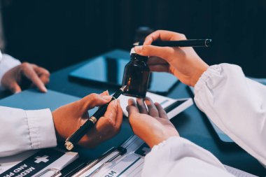 Güvenilir temsilci eczacılık hastanedeki doktor ve hemşire ekibine yeni ilaçlar gösteriyor. Bir grup doktora ilaç şişesini gösteren ve ilaç dozajını açıklayan yetişkin bir uzman..