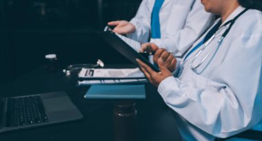 Dijital tablet sağlık doktoru teknolojisi tableti üzerinde çalışan tıbbi ekip hastanedeki tıbbi raporların sonuçlarını analiz etti..