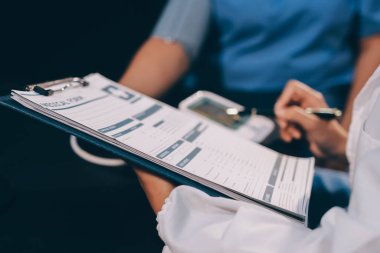 Hastanın tansiyonunu ölçen bir doktor. Hastanın kolunda tansiyon aleti var. Doktor da tansiyon monitörü kullanıyor..