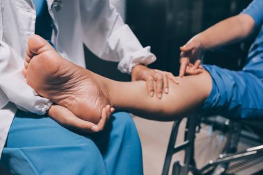 Yaşlı kadın hastanın bacağını iyileştirmek için fizyoterapi yapan fizyoterapist hemşire..