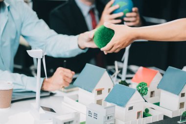 Rüzgar türbini modeli ve ev modeli için mühendisler buluşuyor. Yenilenebilir enerji ve konut geliştirme kavramı. Modern ofiste mimarlardan ve mühendislerden oluşan bir ekip tasarım yapısını tartışıyor..