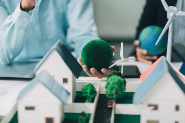 Rüzgar türbini modeli ve ev modeli için mühendisler buluşuyor. Yenilenebilir enerji ve konut geliştirme kavramı. Modern ofiste mimarlardan ve mühendislerden oluşan bir ekip tasarım yapısını tartışıyor..