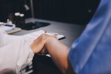 Nazik erkek doktor, beyaz önlüklü danışman yaşlı kadın hasta yaşlı kadının elini tutuyor. Yardım, güvenlik, empati ve destek veriyor, özen ve şefkat gösteriyor. Görüntüyü kapat