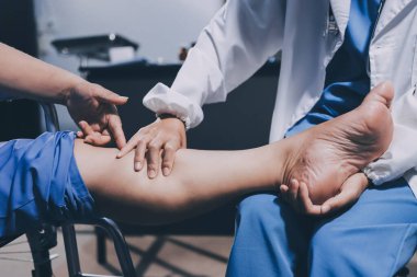 Yaşlı kadın hastanın bacağını iyileştirmek için fizyoterapi yapan fizyoterapist hemşire..