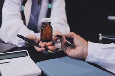 Güvenilir temsilci eczacılık hastanedeki doktor ve hemşire ekibine yeni ilaçlar gösteriyor. Bir grup doktora ilaç şişesini gösteren ve ilaç dozajını açıklayan yetişkin bir uzman..