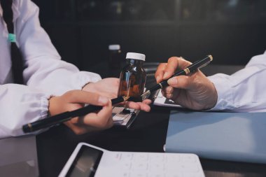 Güvenilir temsilci eczacılık hastanedeki doktor ve hemşire ekibine yeni ilaçlar gösteriyor. Bir grup doktora ilaç şişesini gösteren ve ilaç dozajını açıklayan yetişkin bir uzman..