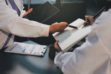 Hastane tıbbı çok etik insanlar grup toplantısı ekibi, aşı eğitimi için hemşire öğrencilerle klinik odasında konuşma. Tablet ve pano tutuluyor.