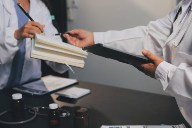 Hastane tıbbı çok etik insanlar grup toplantısı ekibi, aşı eğitimi için hemşire öğrencilerle klinik odasında konuşma. Tablet ve pano tutuluyor.