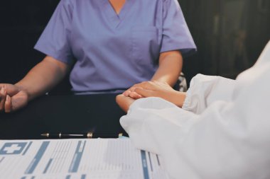 Nazik erkek doktor, beyaz önlüklü danışman yaşlı kadın hasta yaşlı kadının elini tutuyor. Yardım, güvenlik, empati ve destek veriyor, özen ve şefkat gösteriyor. Görüntüyü kapat