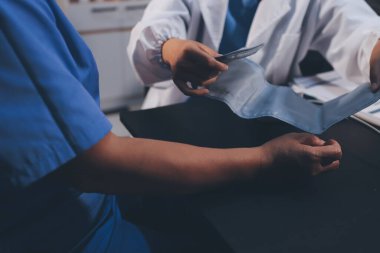 Hastanın tansiyonunu ölçen bir doktor. Hastanın kolunda tansiyon aleti var. Doktor da tansiyon monitörü kullanıyor..