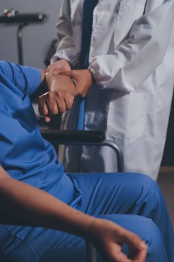 Doktor ya da fizyoterapist, sporcu erkek hastaların yaralı kollarını tedavi ediyor, esneme ve egzersiz yapıyor, klinikte rehabilitasyon tedavisi uyguluyor..