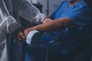 Evde dambıl kullanarak fizyoterapist eğitimi alan yaşlı bir kadın. Terapist, huzurevi egzersizlerinde yaşlı kadına yardım ediyor. Yaşlı bir hasta kollarını uzatmış halterler kullanıyor..