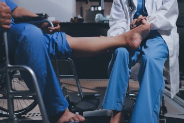 Yaşlı kadın hastanın bacağını iyileştirmek için fizyoterapi yapan fizyoterapist hemşire..