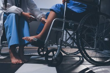 Yaşlı kadın hastanın bacağını iyileştirmek için fizyoterapi yapan fizyoterapist hemşire..