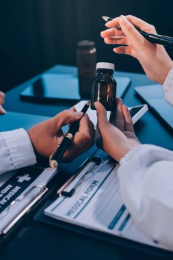 Güvenilir temsilci eczacılık hastanedeki doktor ve hemşire ekibine yeni ilaçlar gösteriyor. Bir grup doktora ilaç şişesini gösteren ve ilaç dozajını açıklayan yetişkin bir uzman..