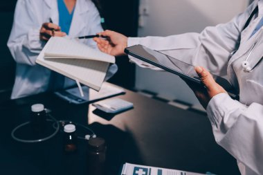 Hastane tıbbı çok etik insanlar grup toplantısı ekibi, aşı eğitimi için hemşire öğrencilerle klinik odasında konuşma. Tablet ve pano tutuluyor.