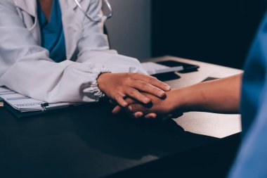 Nazik erkek doktor, beyaz önlüklü danışman yaşlı kadın hasta yaşlı kadının elini tutuyor. Yardım, güvenlik, empati ve destek veriyor, özen ve şefkat gösteriyor. Görüntüyü kapat