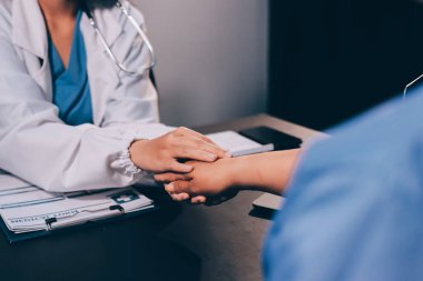 Nazik erkek doktor, beyaz önlüklü danışman yaşlı kadın hasta yaşlı kadının elini tutuyor. Yardım, güvenlik, empati ve destek veriyor, özen ve şefkat gösteriyor. Görüntüyü kapat