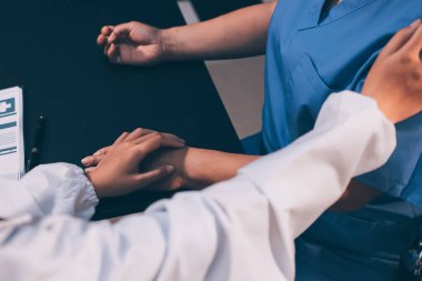 Nazik erkek doktor, beyaz önlüklü danışman yaşlı kadın hasta yaşlı kadının elini tutuyor. Yardım, güvenlik, empati ve destek veriyor, özen ve şefkat gösteriyor. Görüntüyü kapat