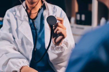 Kadın doktor kaba kalp atışı incelemek için stetoskop kullanın