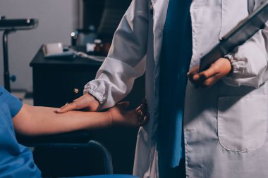 Doktor ya da fizyoterapist, sporcu erkek hastaların yaralı kollarını tedavi ediyor, esneme ve egzersiz yapıyor, klinikte rehabilitasyon tedavisi uyguluyor..