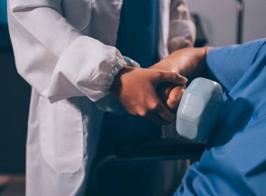 Evde dambıl kullanarak fizyoterapist eğitimi alan yaşlı bir kadın. Terapist, huzurevi egzersizlerinde yaşlı kadına yardım ediyor. Yaşlı bir hasta kollarını uzatmış halterler kullanıyor..