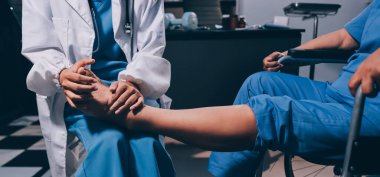 Yaşlı kadın hastanın bacağını iyileştirmek için fizyoterapi yapan fizyoterapist hemşire..