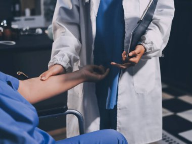 Doktor ya da fizyoterapist, sporcu erkek hastaların yaralı kollarını tedavi ediyor, esneme ve egzersiz yapıyor, klinikte rehabilitasyon tedavisi uyguluyor..