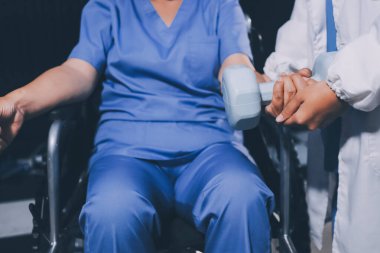 Evde dambıl kullanarak fizyoterapist eğitimi alan yaşlı bir kadın. Terapist, huzurevi egzersizlerinde yaşlı kadına yardım ediyor. Yaşlı bir hasta kollarını uzatmış halterler kullanıyor..