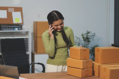 Girişim KOBİ küçük işletme girişimcisi önlük giyen Asyalı kadın dizüstü bilgisayar ve kutu kullanarak çevrimiçi müşterilere, çevrimiçi sme iş fikirlerine satış hazırlamak için siparişleri alır ve gözden geçirir.
