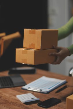 Girişim KOBİ küçük işletme girişimcisi önlük giyen Asyalı kadın dizüstü bilgisayar ve kutu kullanarak çevrimiçi müşterilere, çevrimiçi sme iş fikirlerine satış hazırlamak için siparişleri alır ve gözden geçirir.