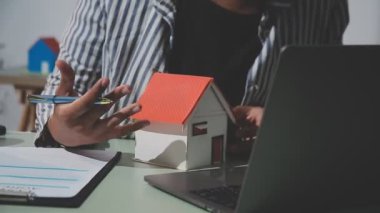 Emlakçı ve anahtarlı genç adam ev modelini tutuyor..