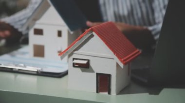 Emlakçı ev modelinin elini tutuyor.